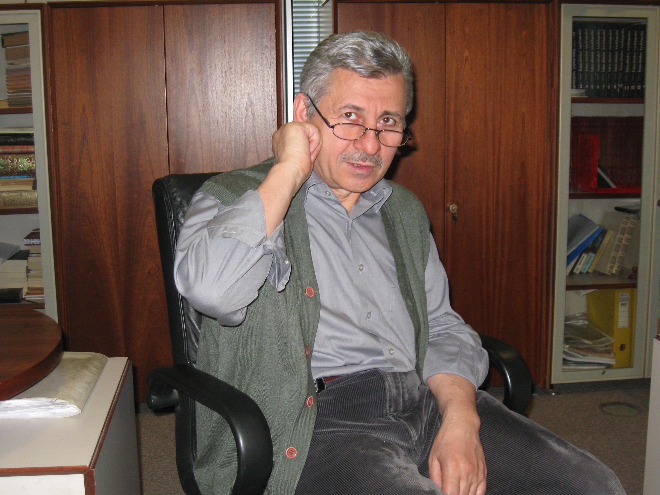 Mehmet Oruç kitaplığının önünde çalışma koltuğunda
